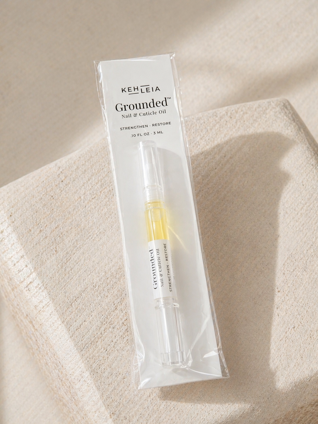 Kehleia Grounded Nail and Cuticle oil pen on a beige fabric background