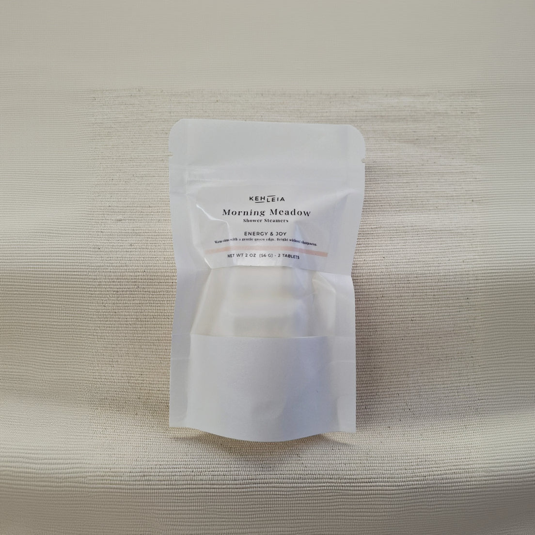 White packaging of Kehleia Morning Meadow shower steamers on a textured beige background